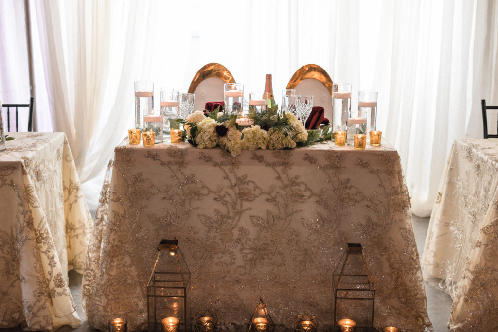 Head table decorated with gold, red, and white creating a simple but elegant look.