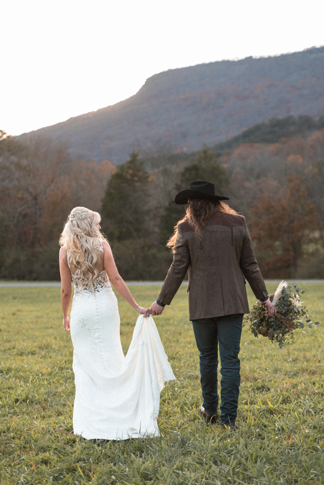 Bride and groom enjoy view of georgia mountains as they walk towards the sunset