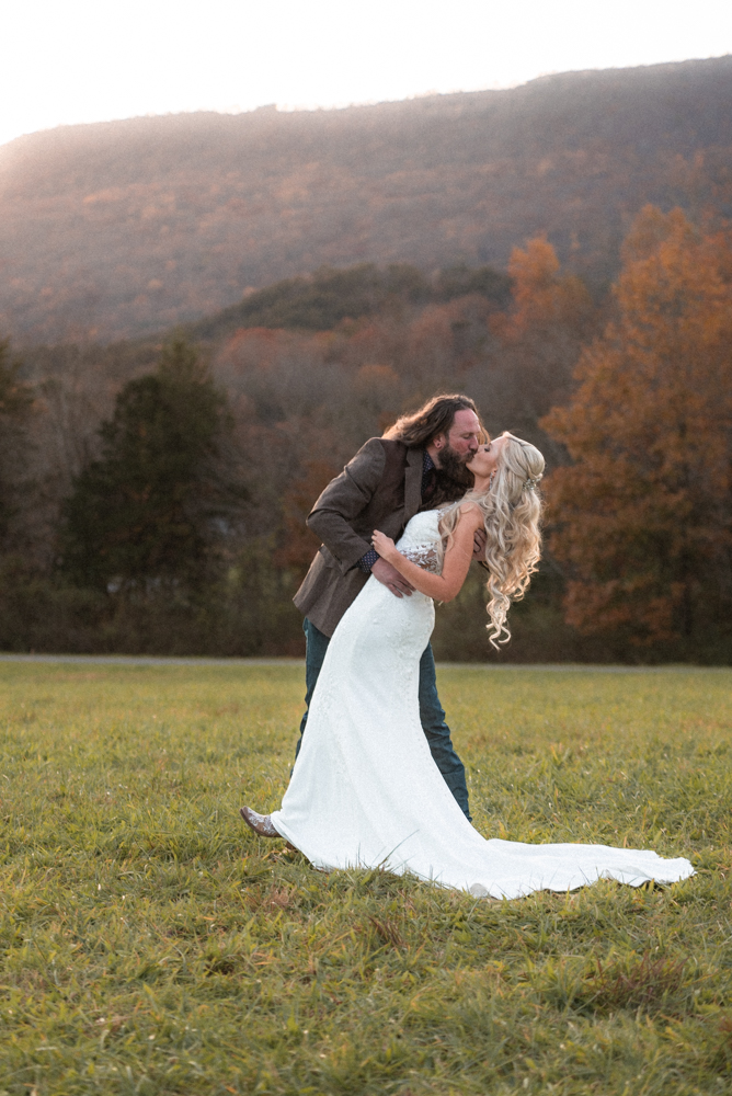 Bride and groom go in for a passionate kiss as the sunsets over the Tennessee mountain range