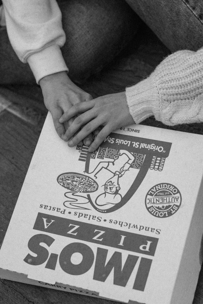 Couples hands meet on St Louis Imo's pizza box s they both reach for a slice of za