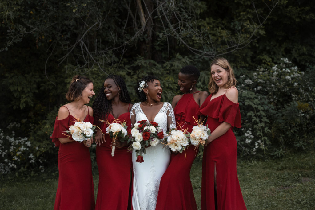 Bride and bridesmaids enjoy time together wearing a stunning red, white, and gold color scheme.