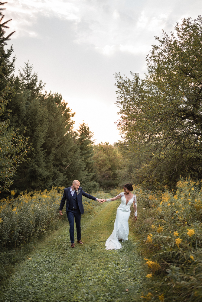 Newly wedded minneapolis couple dance in the field of wild flowers at maidenwood venue.