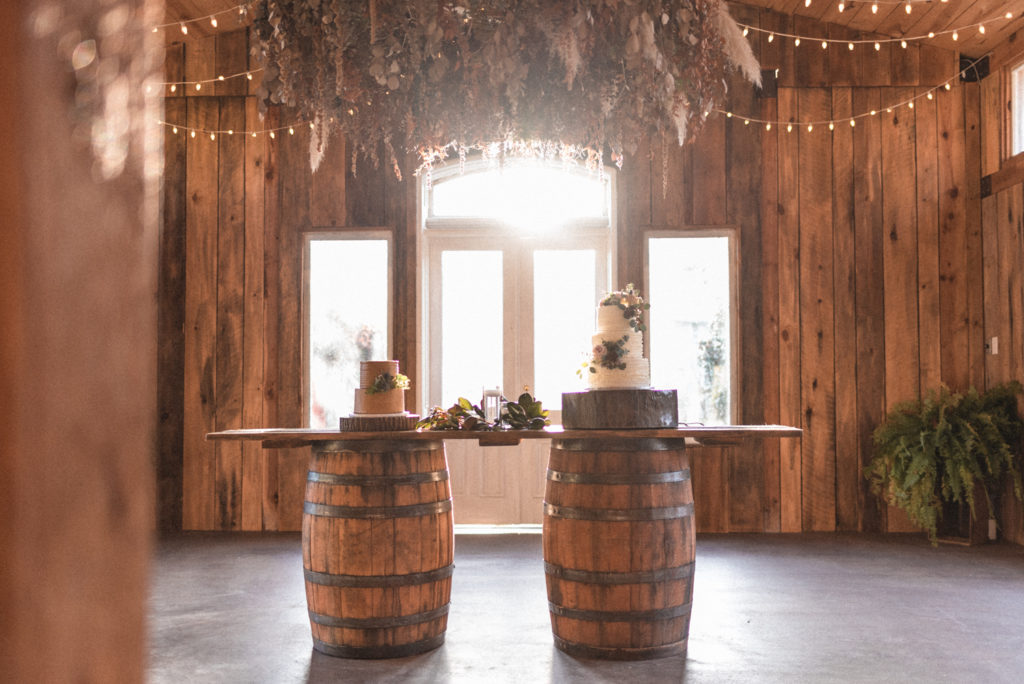 A perfectly boho cake table held with whiskey barrels and perfectly lit by sun's glow