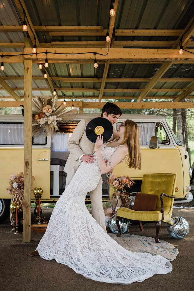 Vintage and boho vibes as the couple hides their kiss behind a vinyl record at lost hill lake venue.