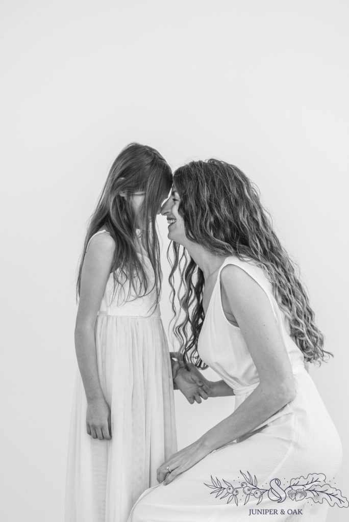 Black and white image of mom and daughter giving eskimo kisses in photography studio north of st louis