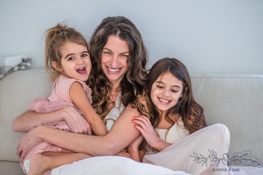 Mom and daughters cuddle on the couch for photo taken by st louis family photographer becky hassel